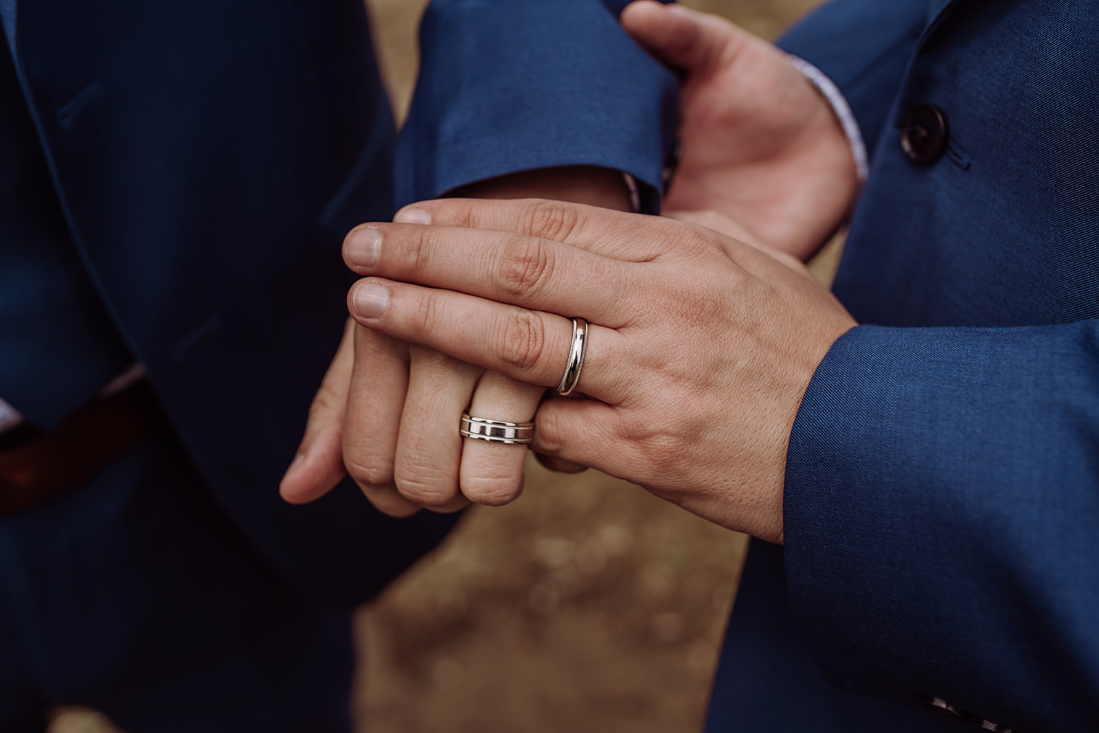 An inclusive and intimate wedding and elopement photographer, Xilo Photography, Kati Douglas who is based in Oakland, California in the bay area, took this picture of a same sex gay couple on their wedding elopement day as the two grooms hold hands and you see an up-close look at their wedding bands as they celebrate their wedding day in their tuxes at Fort Funston, CA which was their intimate wedding venue. Ever wondered what is an intimate wedding or what would be considered a small wedding? This is a great example of both! 